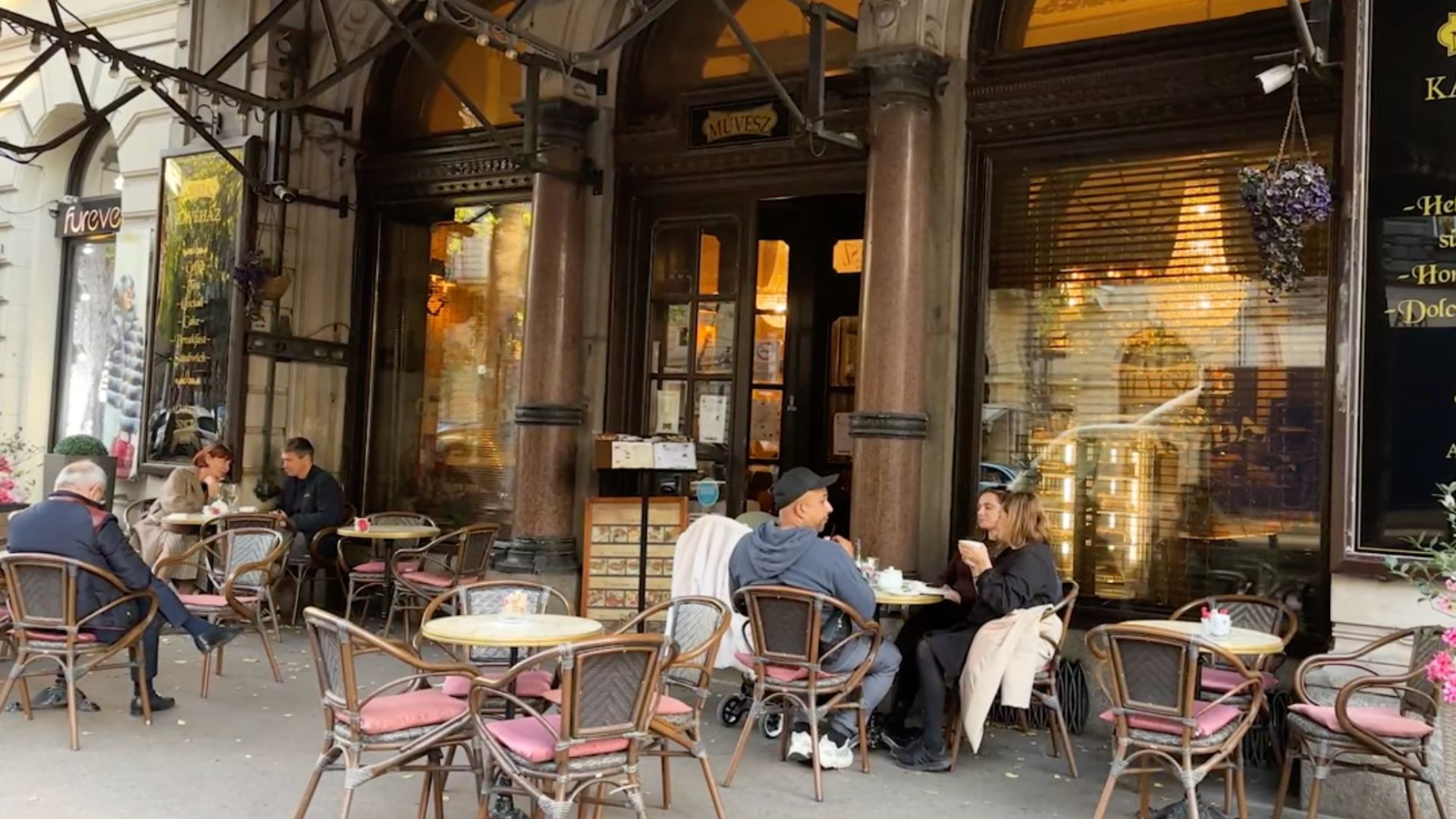 People sitting and enjoying drinks at an outdoor cafe on Andrássy Avenue in Budapest, Hungary.