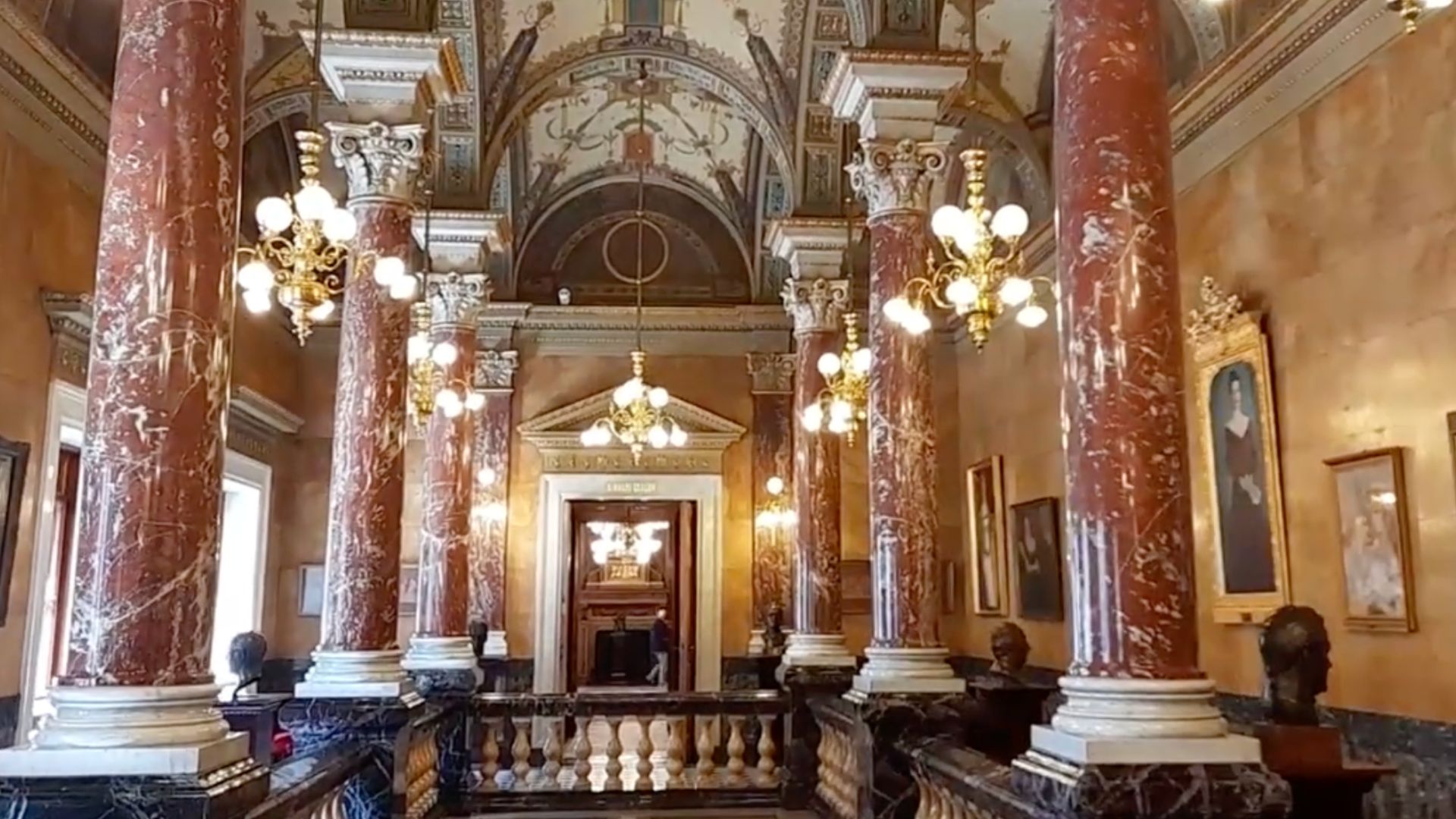 The grand lobby of the Hungarian State Opera House in Budapest, Hungary, with marble columns and chandeliers.
