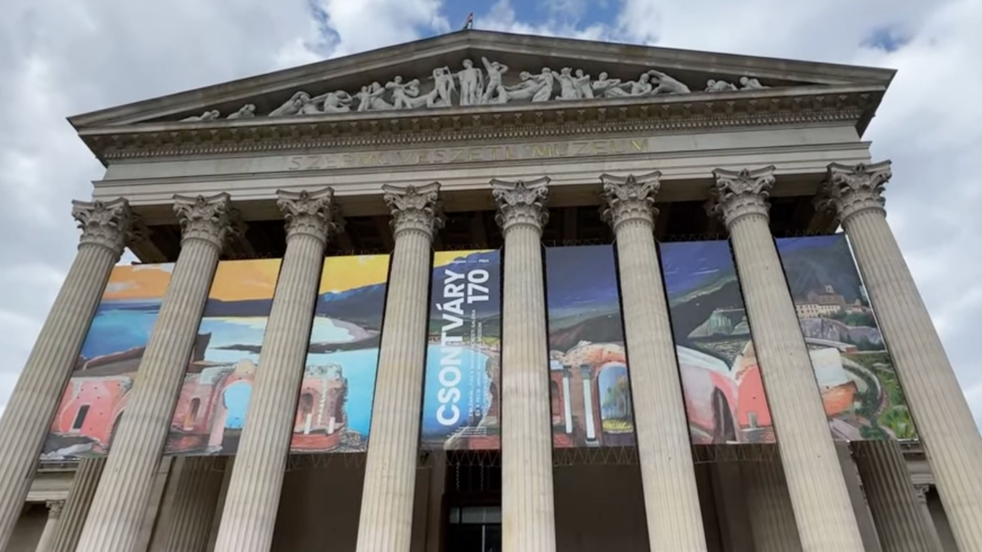 Front view of the Museum of Fine Arts in Budapest, Hungary, with colorful banners and columns.