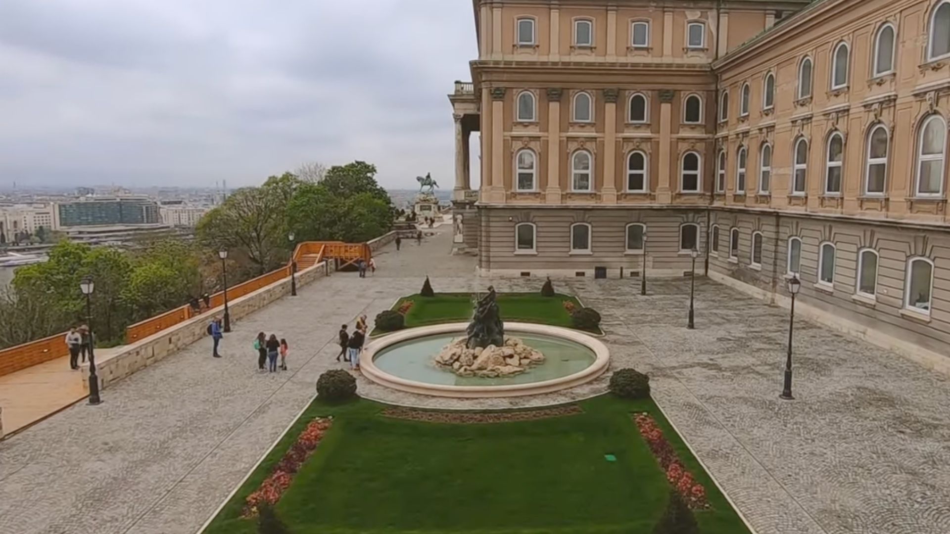 Buda Castle courtyard with a fountain and people walking around.