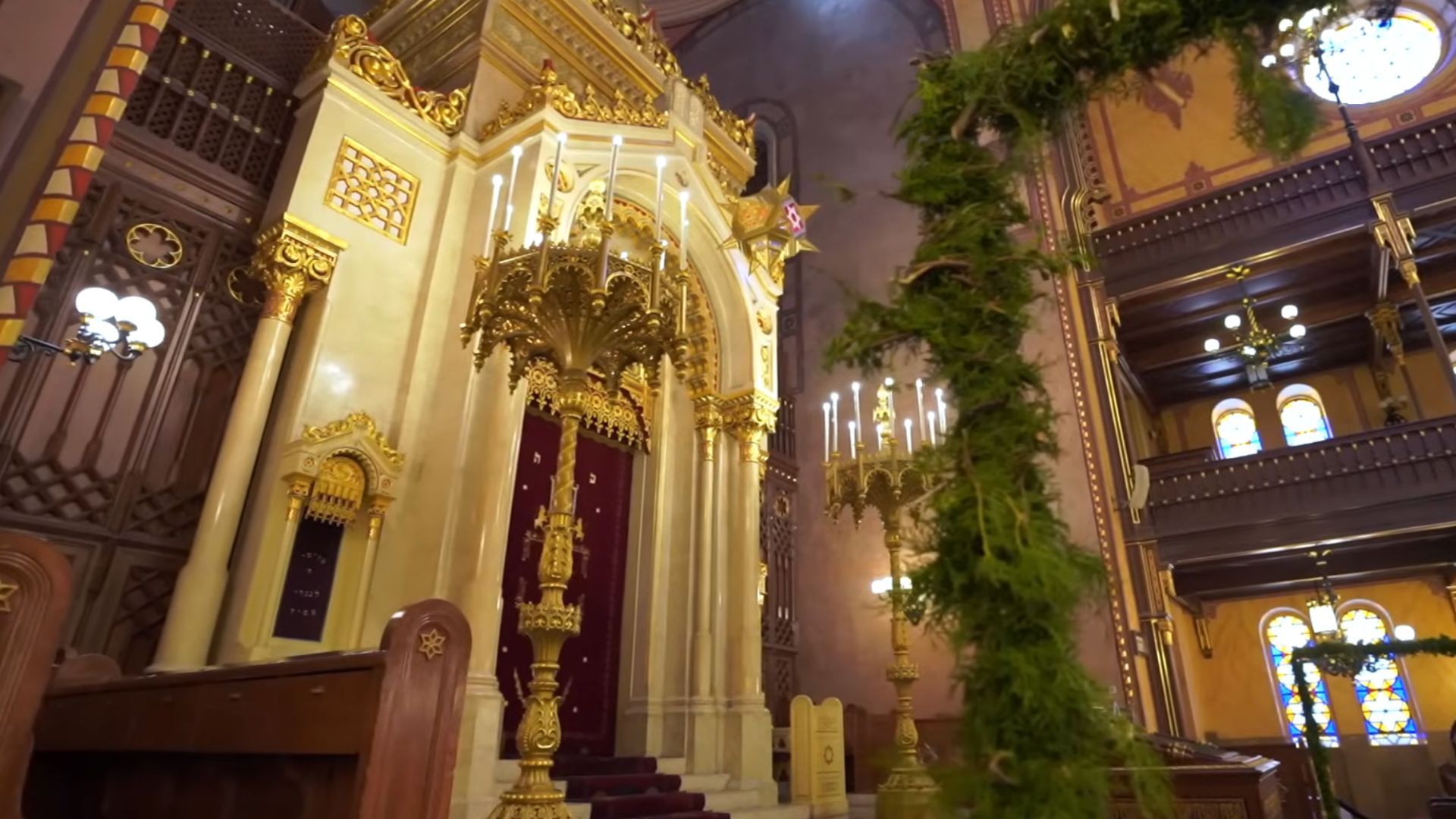 The ornate ark in the Dohány Street Synagogue in Budapest, adorned with gold details, candles, and red curtains, reflecting the grandeur of the synagogue's interior.