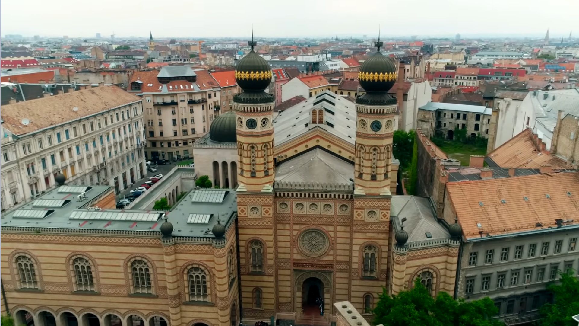 Aerial front view of the Dohány Street Synagogue in Budapest, highlighting the intricate design of the facade and the large dome of the adjacent building.