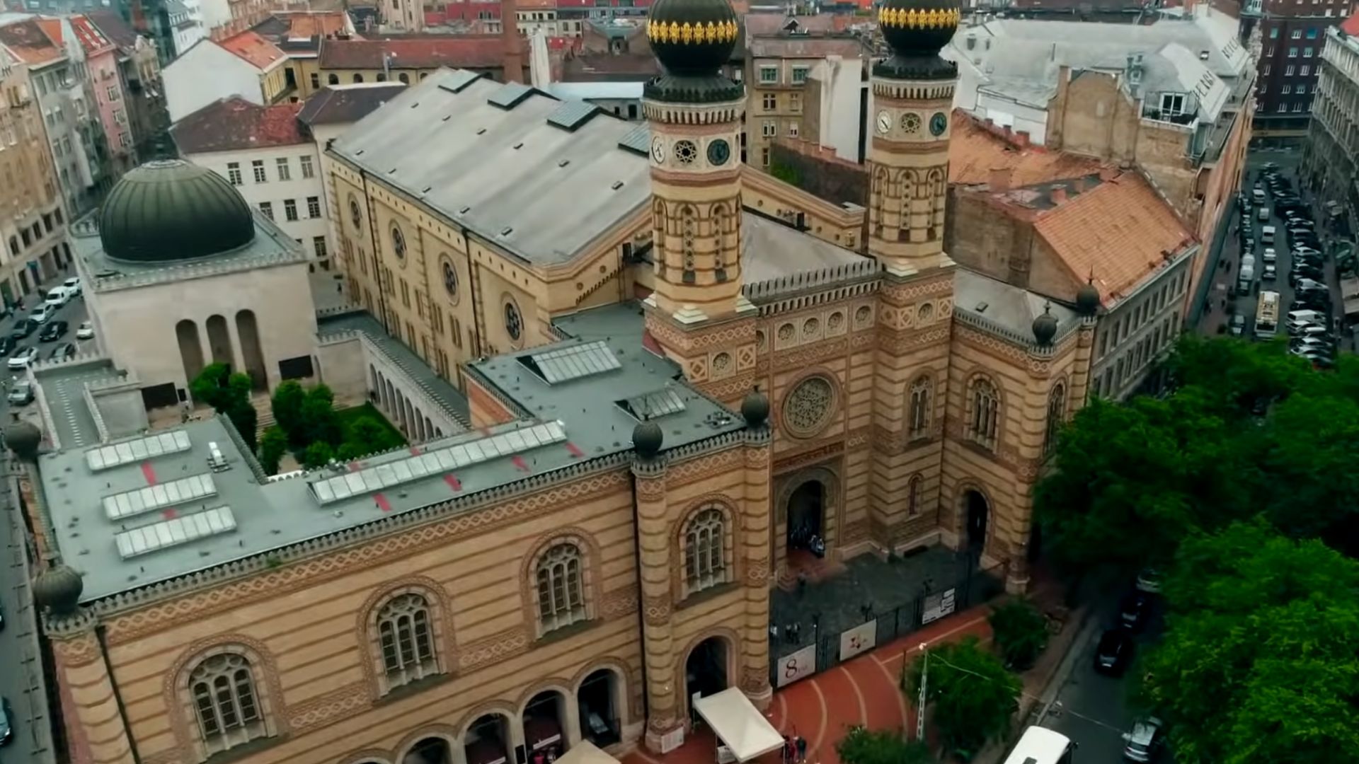 Aerial view of the Dohány Street Synagogue in Budapest, showcasing its ornate facade, twin towers, and surrounding buildings in the historic Jewish Quarter.