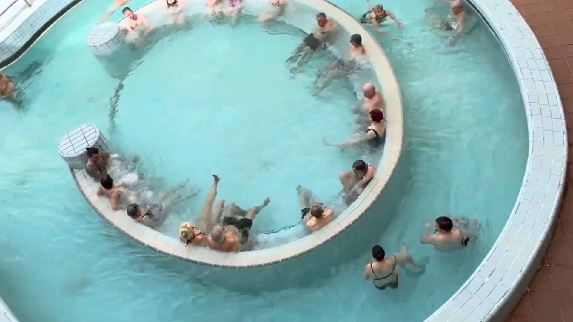 Circular section of a thermal pool at Lukács Thermal Bath in Budapest, with people sitting around the edge in warm water.