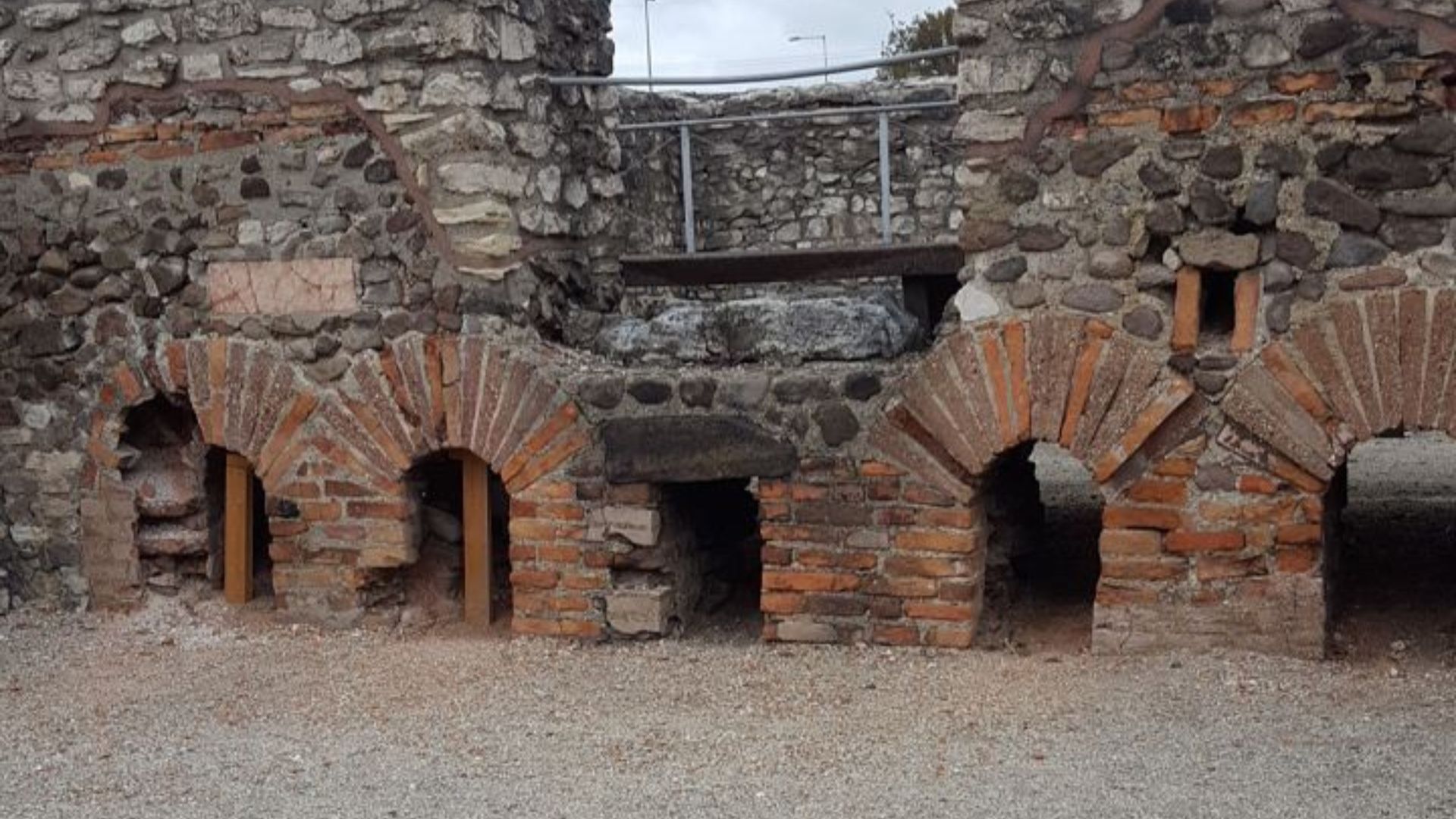 Ancient brick arches and stone walls at Aquincum, showcasing Roman architectural remnants with visible details of masonry and archways.